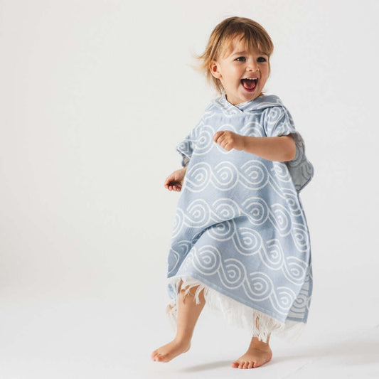 Bamboo Kids Bath Poncho - Light Blue worn by a happy child playing, showcasing soft bamboo and cotton blend.